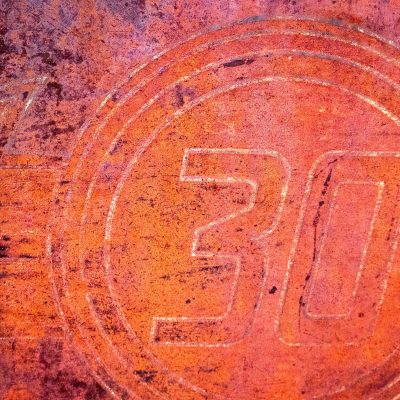 A textured, rusty orange metal surface with the embossed number 30 circled by stamped lines.