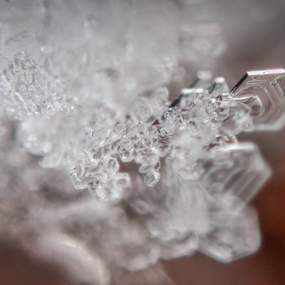 Macro photo of sharp hexagonal ice crystals with a blurred, warm-toned background.