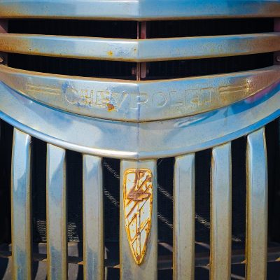 Detailed view of a classic Chevrolet grille with rusted chrome bars and emblem.